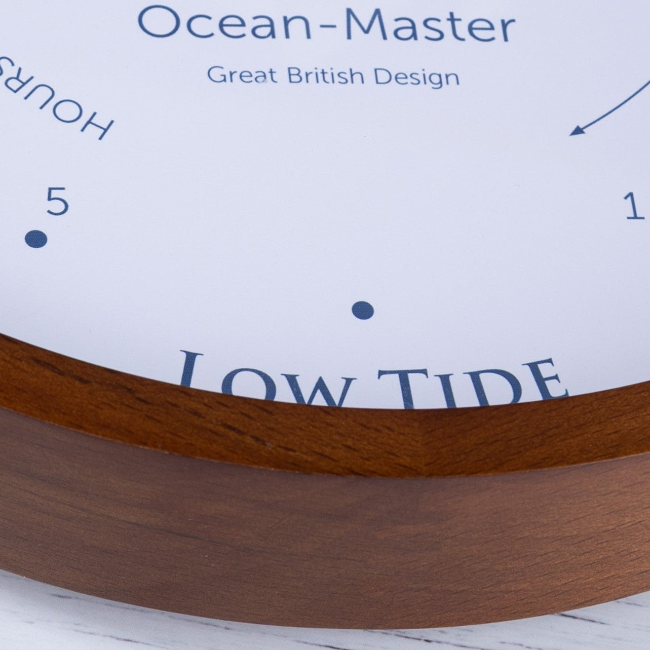 Wooden tide clock with white face displaying 'Ocean-Master' brand on a light wooden surface.