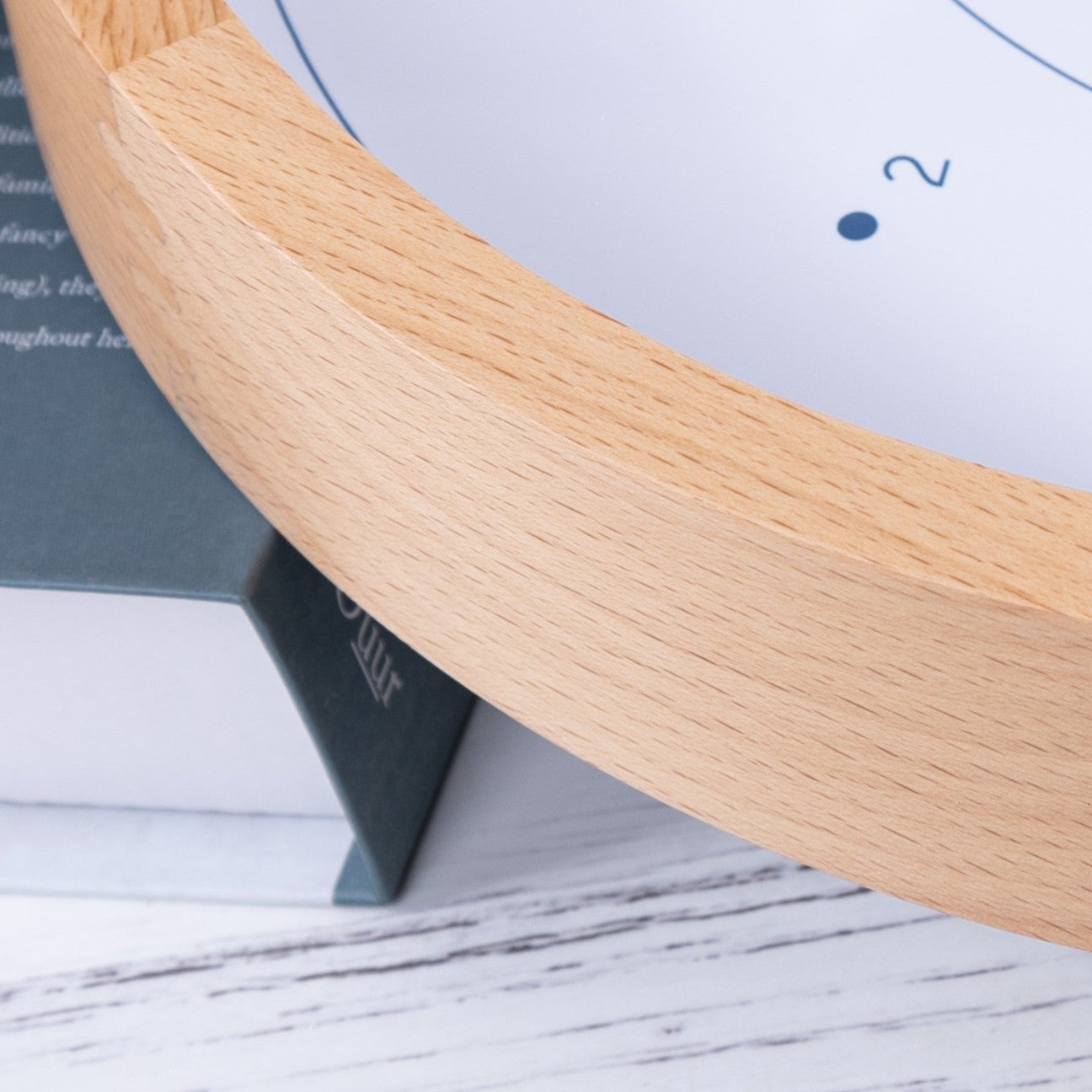 Wooden clock with white face on a light wooden surface